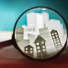 Magnifying glass over paper homes